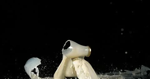 Bottle of Milk Exploding against Black Background Stockfoto's