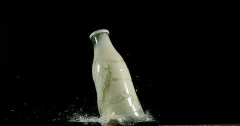 Bottle of Milk Exploding against Black Background Stock Photos