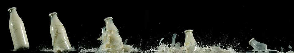 Bottle of Milk Exploding against Black Background Stock Photos