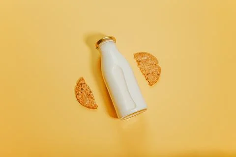 A bottle of milk surrounded by two pieces of one cookie Stock Photos