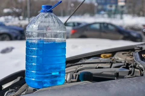 Bottle with non-freezing liquid for windshield washer standing on the engine Фото