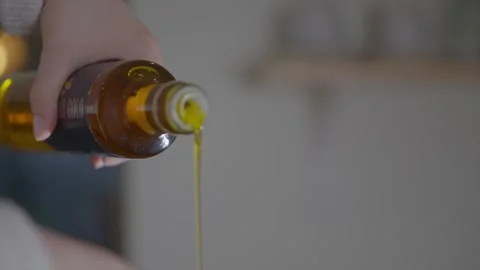 A bottle of oil is being poured into a container Stock Footage 306043693