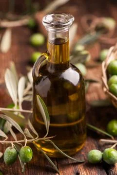 Bottle of olive oil aand olves on wooden table Stock Photos