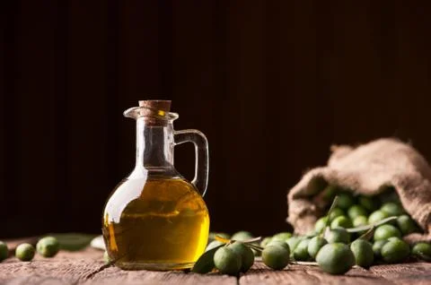 Bottle of olive oil aand olves on wooden table Stock Photos