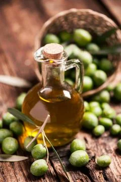 Bottle of olive oil aand olves on wooden table Stock Photos