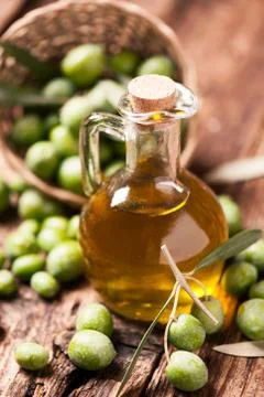 Bottle of olive oil aand olves on wooden table Stock Photos