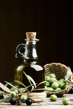 Bottle of olive oil aand olves on wooden table Stock Photos