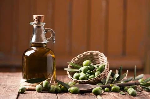 Bottle of olive oil aand olves on wooden table Stock Photos