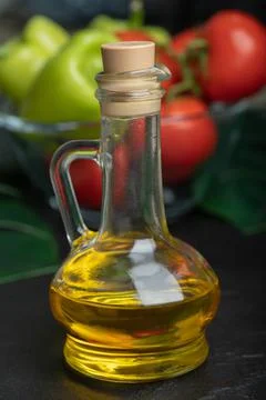 Bottle of olive oil in front of fresh vegetables Stock Photos