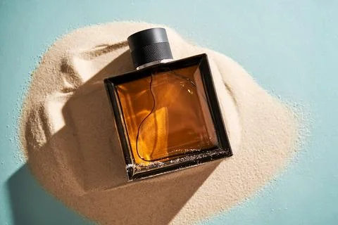 A bottle of perfume on a background of sand. Stock-Fotos