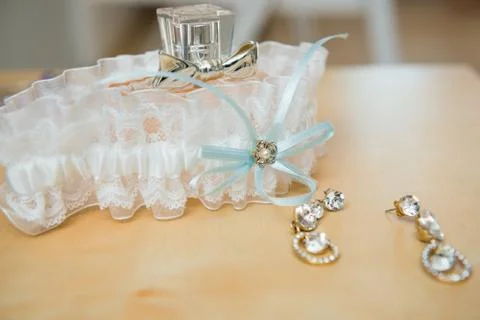 Bottle of perfume, garter of bride and earrings on wooden table. Wedding Them Stock Photos