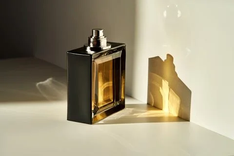 A bottle of perfume in the rays of the sun. Stock Photos