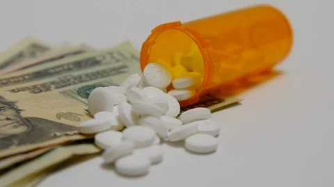 Bottle of pills spilled out onto stack of money. Stock Footage 108033432