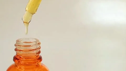 Bottle pipette dropper and dripping sticky liquid yellow-orange vitamin c serum Stock Footage 284535342