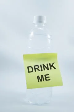 Bottle plastic with a sticky note that says: drink me. isolated on white. Stock Photos