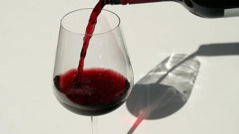 Bottle pours red wine into empty wine glass with shadow Vidéo 115512861