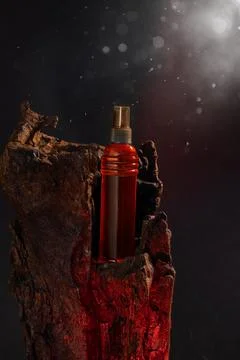 Bottle with red liquid resting in a piece of wood against a dark background with Stock Photos