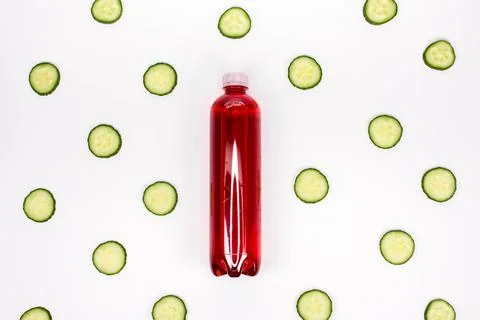 Bottle of red smoothie on white background with cucumber pattern. Top view. Stock Photos