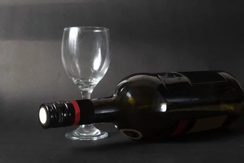 Bottle of red wine and empty wine glass on a black background. copy space Stock Photos