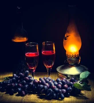 A bottle of red wine and two glasses in the dim light from a kerosene lamp Stock Photos