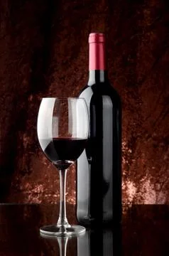 Bottle of red wine and a wineglass on a table on brown background Stock Photos