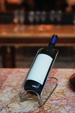 A bottle of red wine on a stand with an empty label Stock Photos