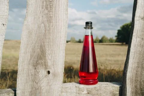 Bottle with refreshing red lemonade in backlight outdoors 스톡 사진