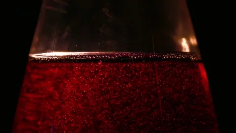 A bottle of ruby red carbonated drink on a dark background with thin bubbles Stock Footage 320419457