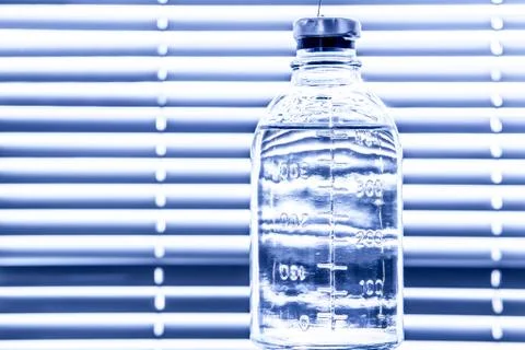 A bottle of saline on the background of blinds Stock Photos
