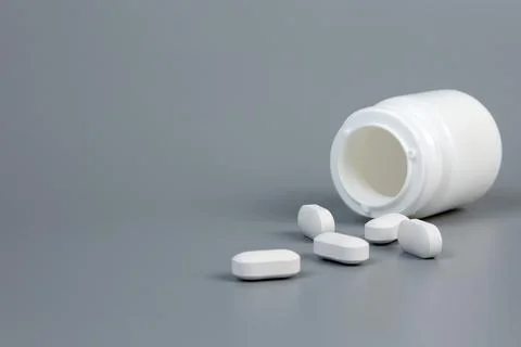 A bottle with scattered tablets on a gray background Stock Photos