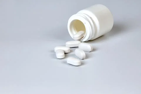 A bottle with scattered tablets on a gray background Stock Photos