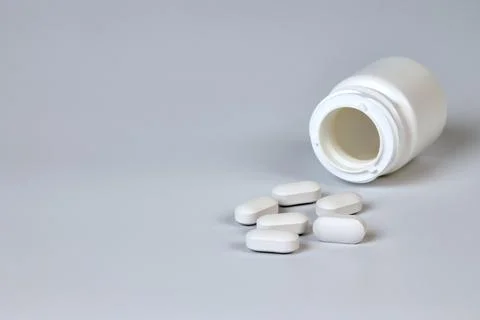 A bottle with scattered tablets on a gray background Stock Photos