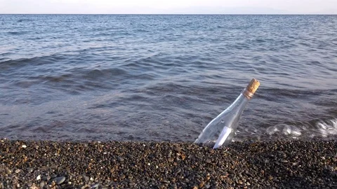 Bottle washed up by waves with a letter in it Stock Footage 73301319