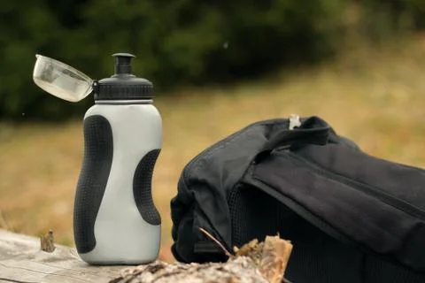 A bottle of water and a backpack on the grass. The concept of recreation in t Stock Photos