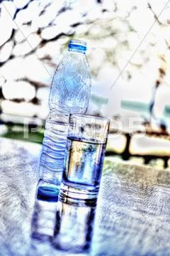 A Bottle Of Water And A Glass Of Water On A Table