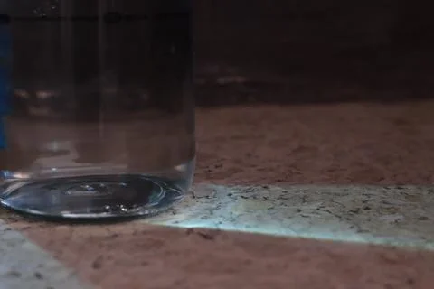 A bottle of water with glare on the table. Multi-colored glare of water in bottl Stock Photos