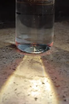 A bottle of water with glare on the table. Multi-colored glare of water in bottl Stock Photos