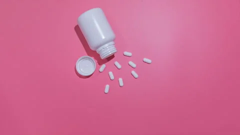 Bottle with white pills gets empty on pink plain background. Stop Motion Stock Footage 170838866