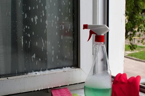 Bottle of window cleaner on dirty window Stock Photos