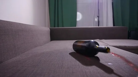 A bottle of wine falls on the sofa and spills wine. Video stock 122849404