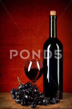 Bottle of wine, glass and grapes over red grunge background Stock Photos