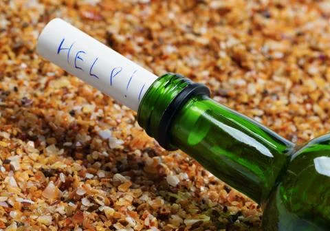Bottle of wine with help message on sand in beach at sun summer day Stock Photos