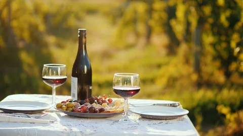 A bottle of wine with snacks is on the table. In the background, blurred Stock-Footage 98297004