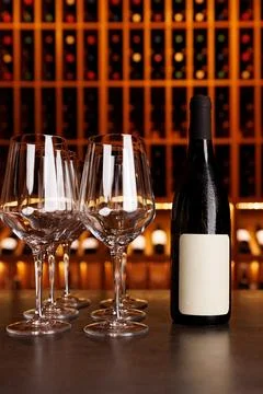 A bottle of wine is on a table next to four wine glasses Stock Photos