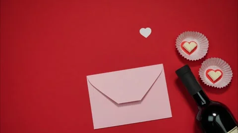 Bottle of Wine, Two Heart Shaped Candies And Pink Envelope on Red Background. Stock Footage 320960543