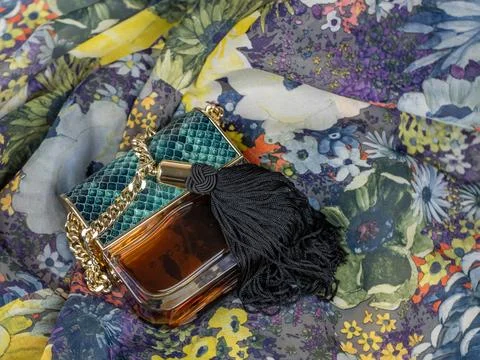A bottle of women's perfume on a background of multi-colored motley fabric. A Stock Photos