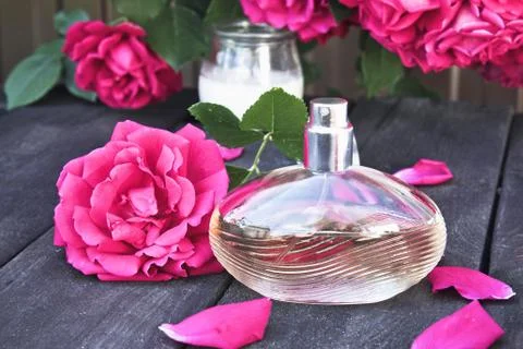 Bottle of women's perfume with red roses on the background of dark wooden boa Stock Photos