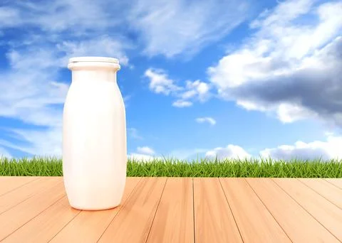 Bottle of yogurt on the table on background of grass and sky Illustrazione stock