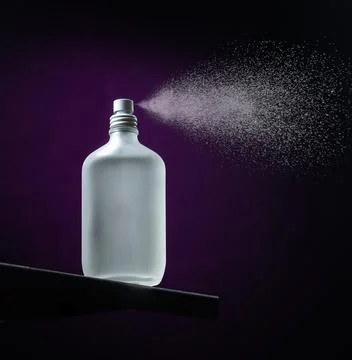 Bottled aromatic diffuser spraying isolated on a purple and black background Foto stock