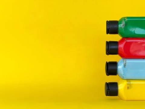 Bottles with bright multi-colored acrylic paint on a yellow background Stock Photos
